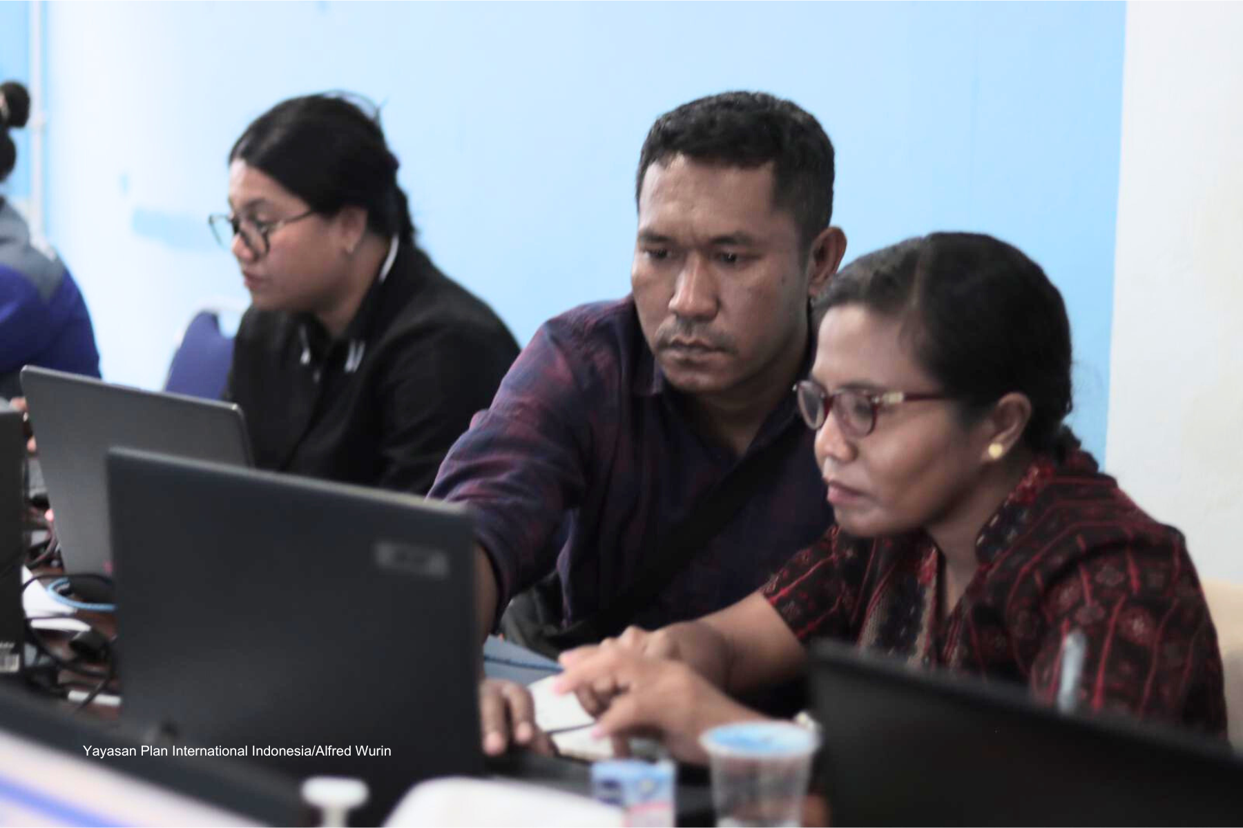 A man guiding a woman in glasses to work with her laptop.