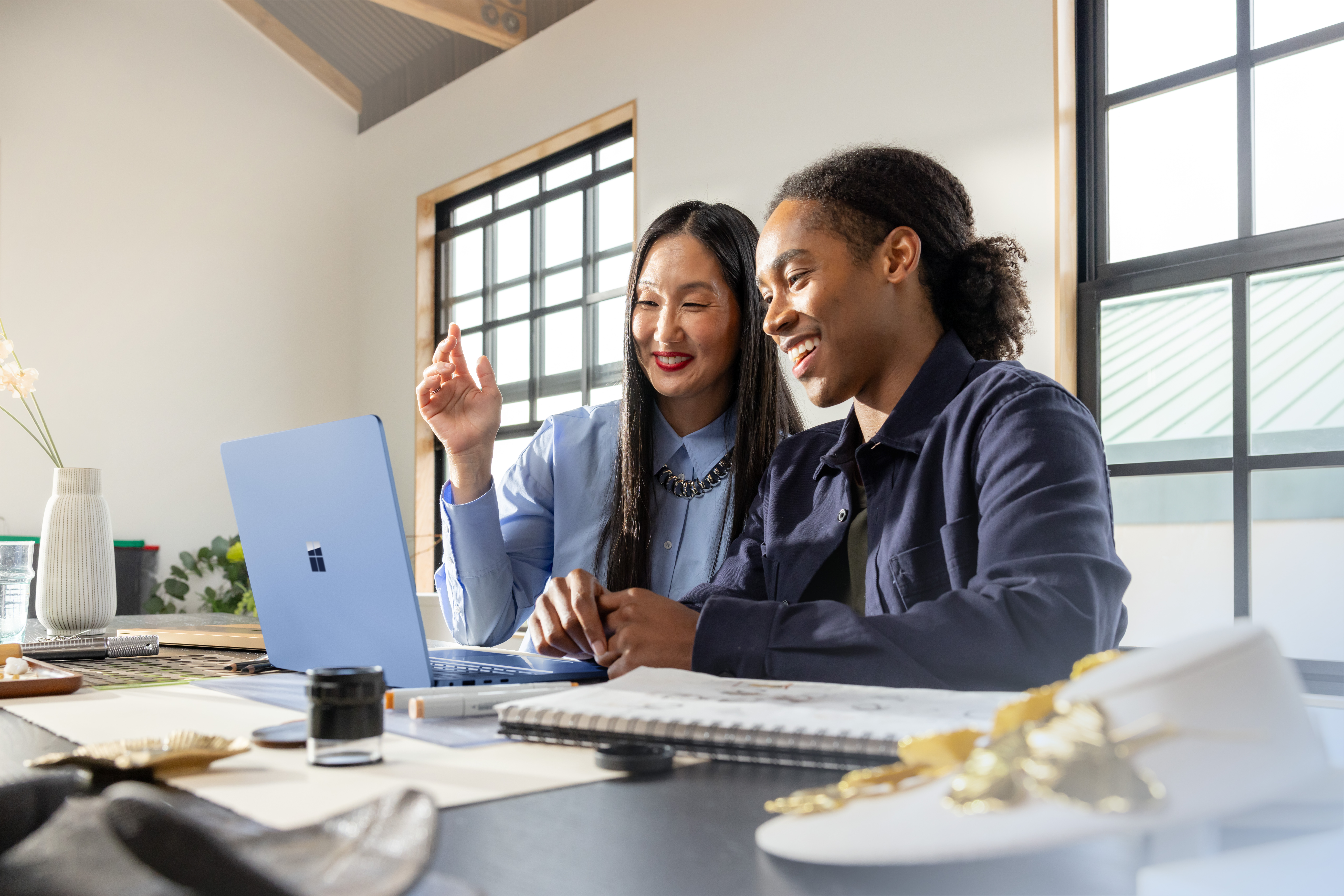 Man and woman collaborate in front of a Surface laptop
