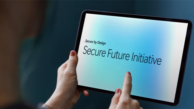 a tablet held in a hand with "Secure by design, Secure Future Initiative" written on its display